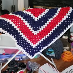 a crocheted blanket sitting on top of a wooden table next to other items