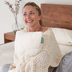 a woman is sitting on her bed holding a pillow