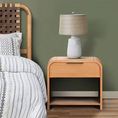 a nightstand with a lamp on top of it next to a bed in a bedroom