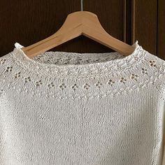 a white sweater hanging on a wooden hanger