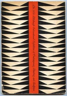 an old book with black and white designs on the front, red ribbon at the bottom