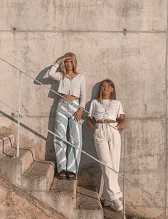 two women are standing on the stairs and one is holding her hand up to her face