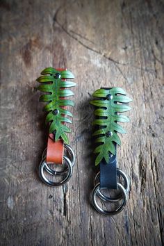 two metal key chains with green leaves on them