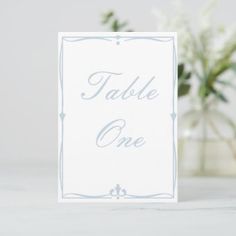 a card with the words table one on it next to a vase filled with flowers