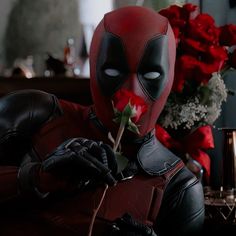 the deadpool is holding a rose in his hand and looking at it with eyes wide open