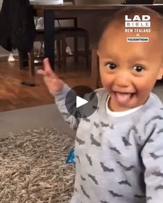 a baby is smiling and waving at the camera with his hands in front of him