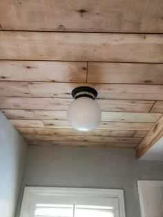 a light fixture hanging from the ceiling in a room with white walls and wood paneling