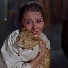 a woman holding a cat in her arms and smiling at the camera with tears on her face