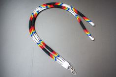 a multicolored lanyard on a gray surface with a white hook and black cord