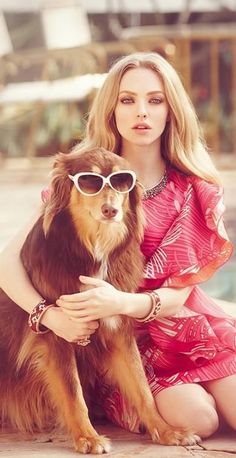 a woman is sitting on the ground with her dog and wearing sunglasses that look like they are hugging each other