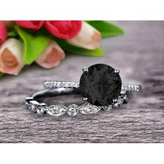 a black diamond engagement ring set on top of a wooden table with flowers in the background