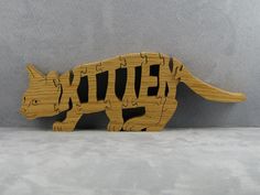 a wooden puzzle with the word kitten on it's side and a cat in the middle