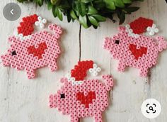 three pieces of pink and red perler bead art hanging on a white wooden surface