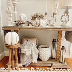 a wooden table topped with white pumpkins and other decorative items on top of it