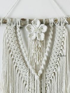 a white wall hanging with tassels and flowers