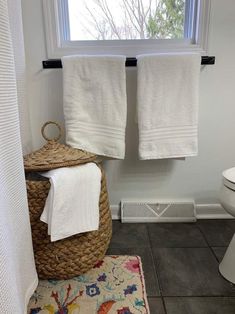 a bathroom with two white towels hanging on the wall and a basket next to it