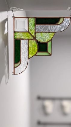 a green and white stained glass window hanging from the ceiling in a room with other items