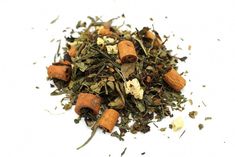 a pile of green tea with cinnamons and other things around it on a white surface