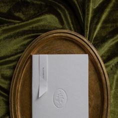 a white book sitting on top of a metal plate next to a green velvet cloth