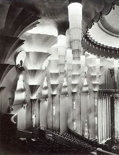 an old photo of the inside of a building with columns and chandeliers hanging from the ceiling