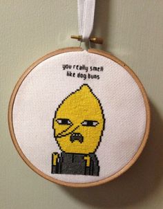 a cross - stitch hoop hanging on the wall with a cartoon character saying, you really smell like dog buns