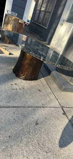 a wooden bench sitting on the side of a road next to a building with windows