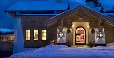 a house is lit up at night with snow on the ground and christmas decorations in front