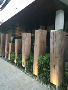 a row of wooden poles sitting next to each other in front of a building with plants growing on it