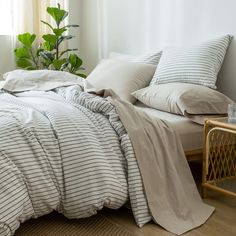 an unmade bed with white and grey striped sheets