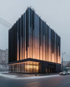 the building has many windows and is lit up in the evening light with snow on the ground