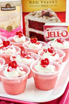 cupcakes with white frosting and cherries in plastic cups on a tray