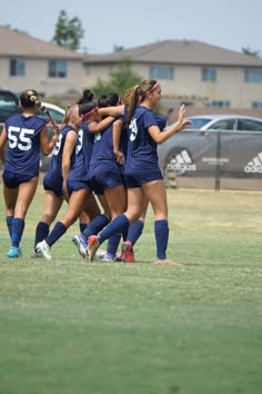 a group of girls playing soccer on a field with their hands in the air as they celebrate