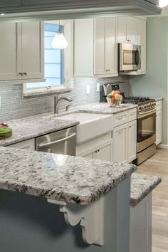 a kitchen with white cabinets and granite counter tops