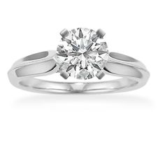 a white gold engagement ring with a round diamond in the center and an engraved band