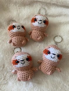 three crocheted keychains that have been placed on a white blanket with one stuffed animal in the middle