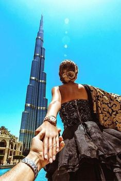 two people are holding hands in front of a burj building and blue sky