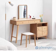 a wooden desk with a mirror and stool next to it in a room that has white walls