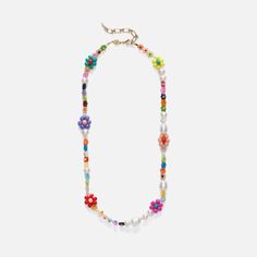 a multicolored beaded necklace with flowers on it, hanging from a gold chain