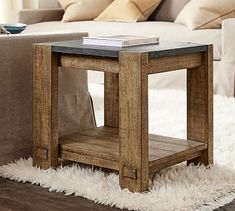 a wooden table sitting on top of a white rug in front of a living room couch