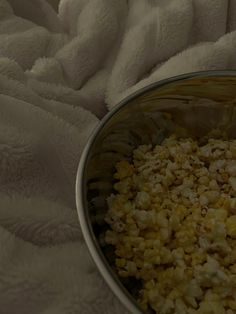 a metal bowl filled with food on top of a white blanket