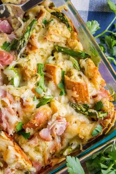 a casserole dish with ham, asparagus and cheese in it on a blue table cloth