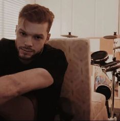 a man sitting on top of a couch next to a drum set