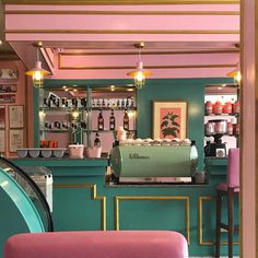 the interior of a coffee shop with pink and green walls, gold trimmings and bar stools