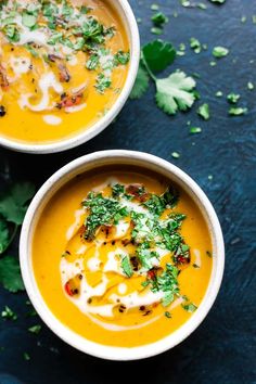 two white bowls filled with soup and garnished with parsley