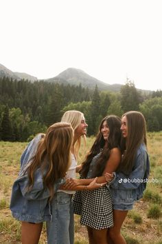 four young women standing together in a field