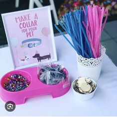 there is a pink tray with plastic straws and other items on it next to a sign that says make a collar for your pet