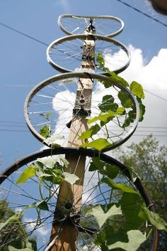 an upside down metal sculpture with plants growing out of it's sides and the sky in the background