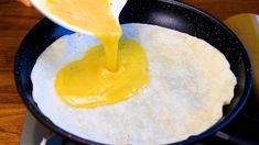 someone pouring sauce on top of an omelet in a skillet with a spatula