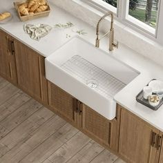 a kitchen sink sitting under a window next to a counter top with bread on it