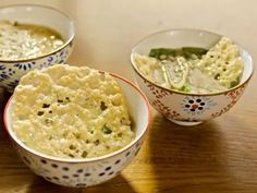 three bowls filled with food sitting on top of a wooden table next to each other